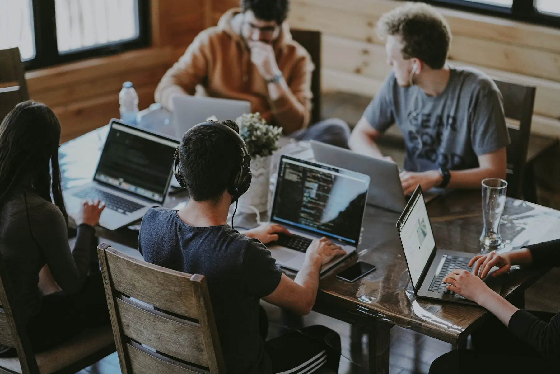 Équipe réunie autour d'une table de travail avec des ordinateurs portables