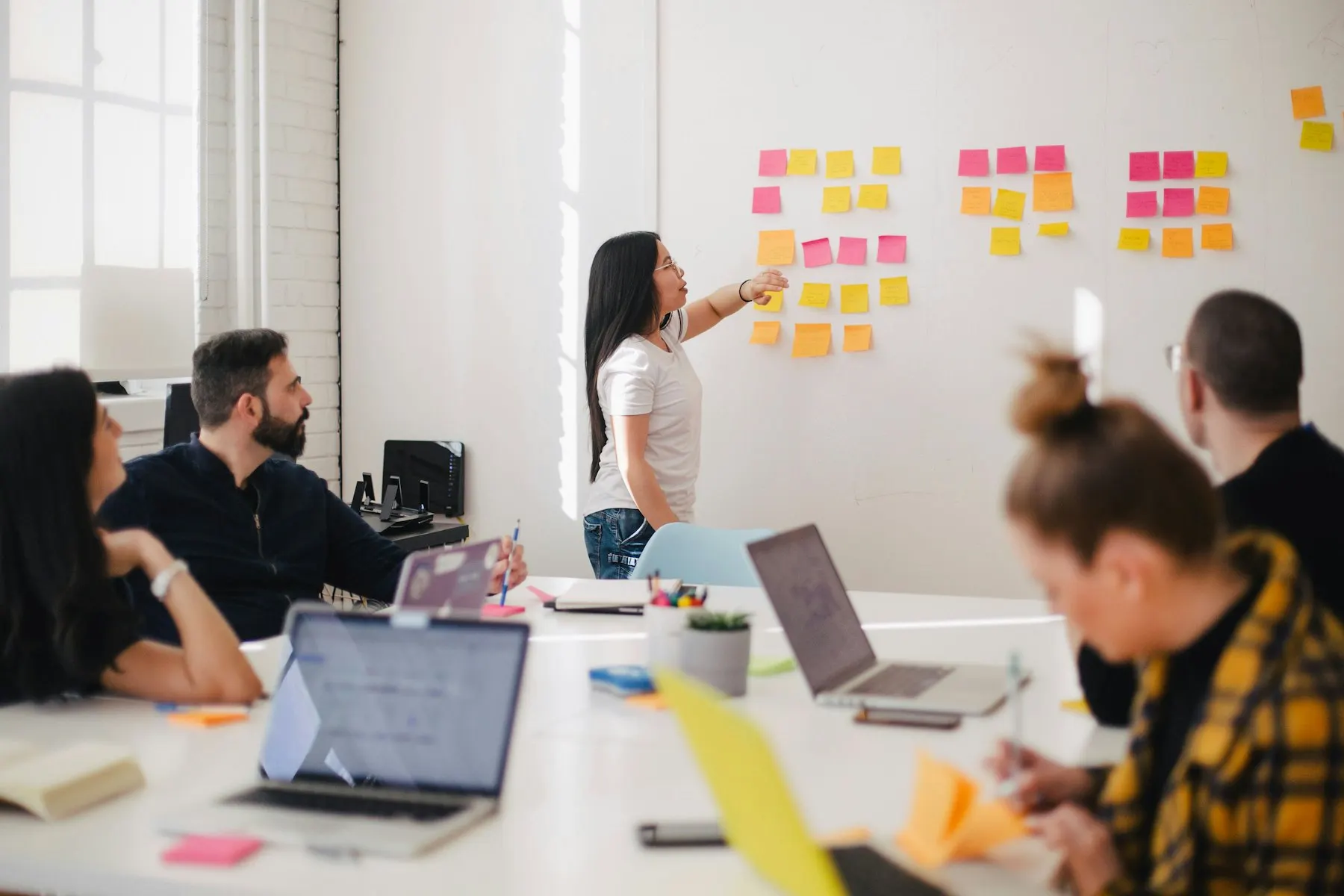 Atelier de travail : une personne organise des notes repositionnables sur un mur devant une équipe